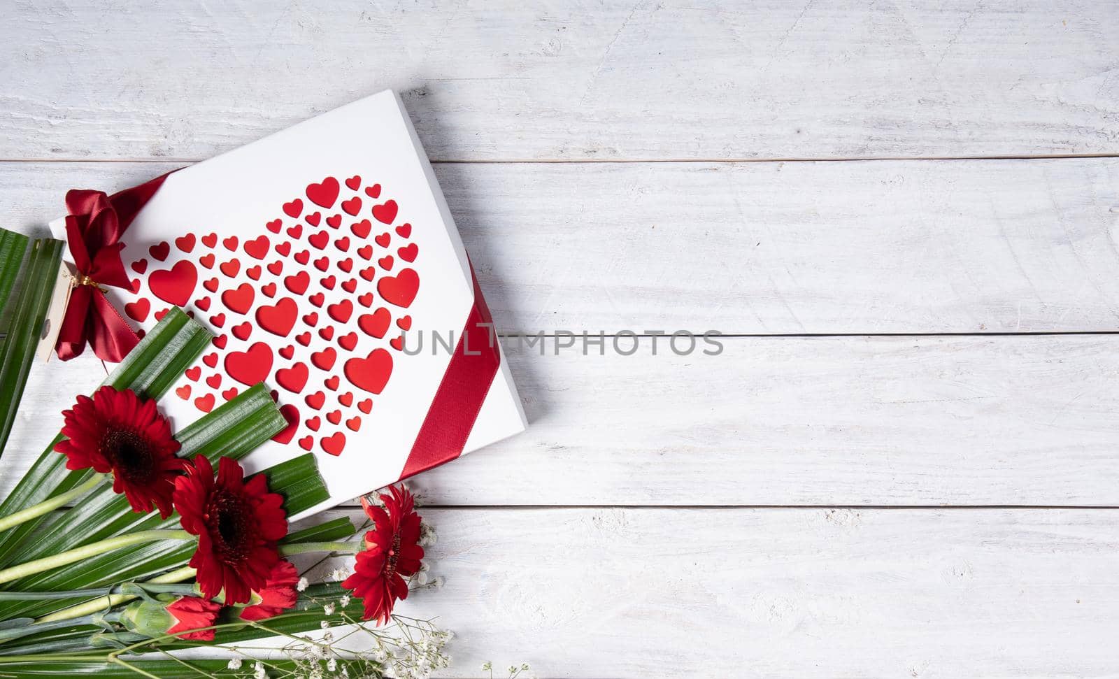 Valentine's day gift, red heart praline box and flower bouquet on white table by KaterinaDalemans