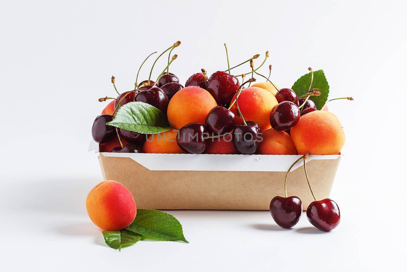 Apricots and cherries in paper packaging on a white background. the concept of eco-friendly packaging without plastic.