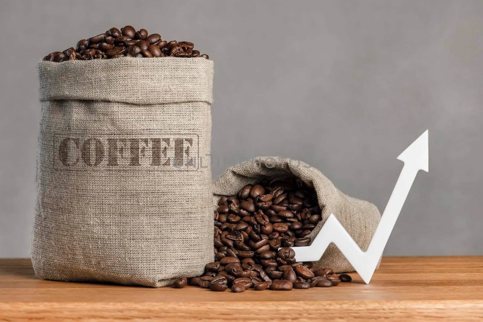 A bag of coffee beans and a chart arrow pointing up. The cost of coffee in the markets of the world. The concept of the growth of the cost of coffee beans.