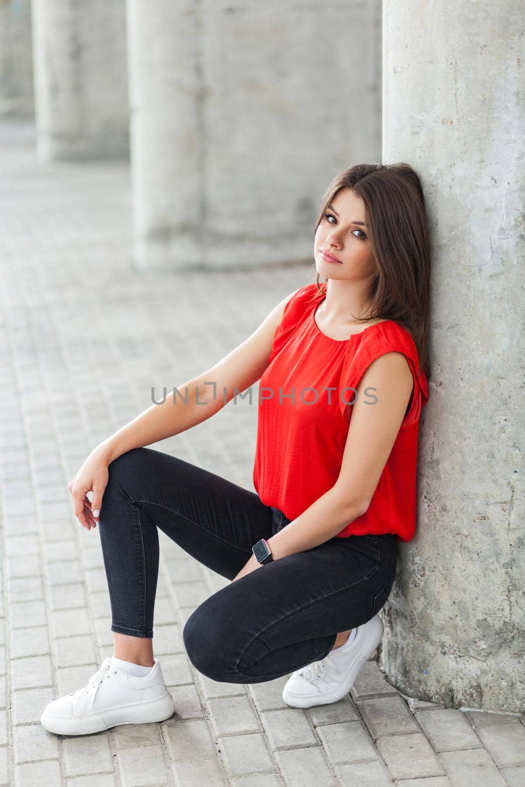 beautiful woman in casual style clothes sitting near grey column at street. outdoor shot