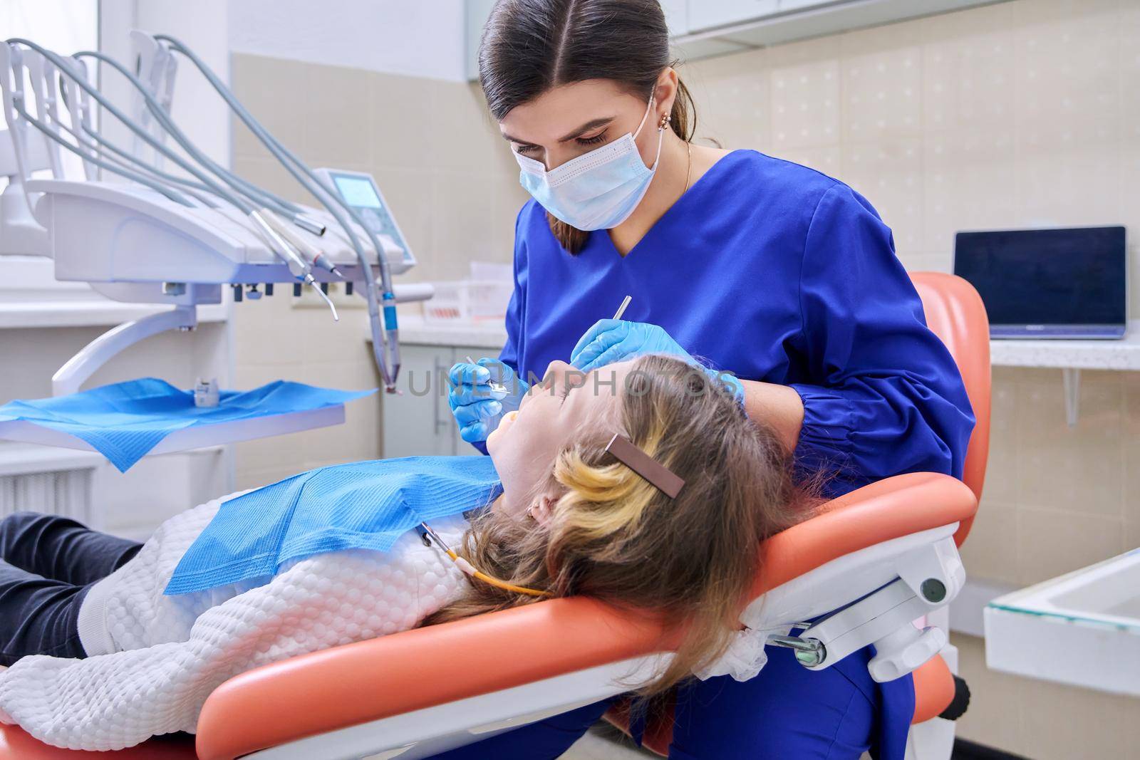 Female doctor dentist treats teeth to a child girl using anesthesia. Treatment, dentistry, children, health, dental care concept