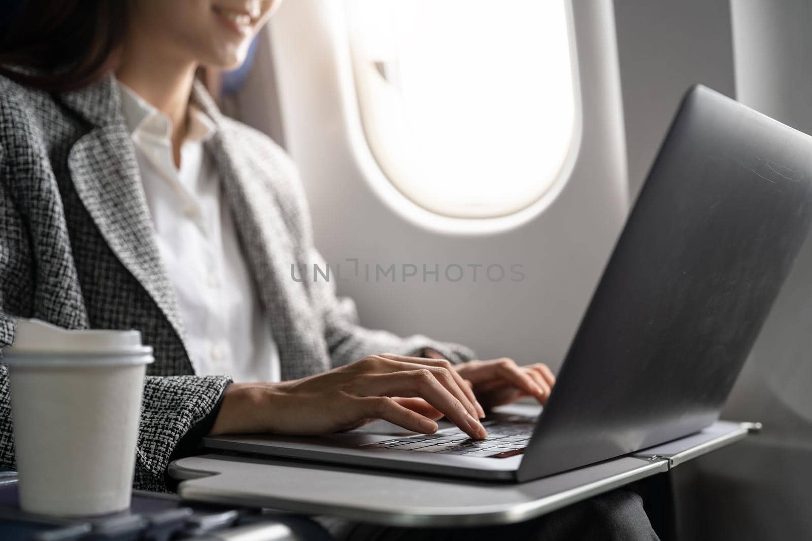 Close up hand of business asian woman uses laptop while flying on airplane near window. by nateemee