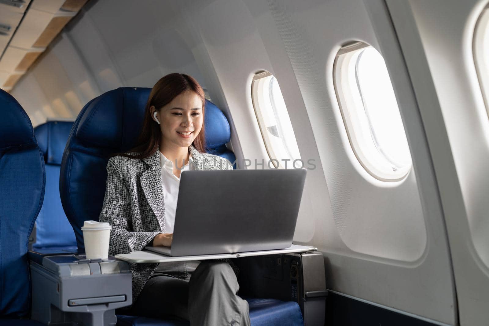 Close up hand of business asian woman uses laptop while flying on airplane near window