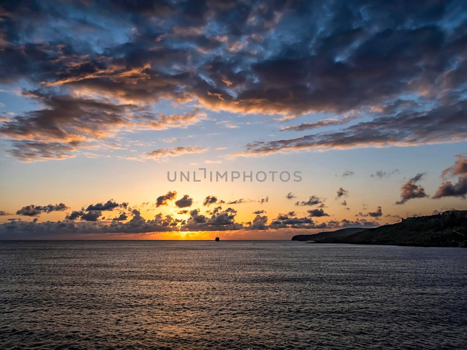 Amazing sunset over the sea with a ship on the horizon.