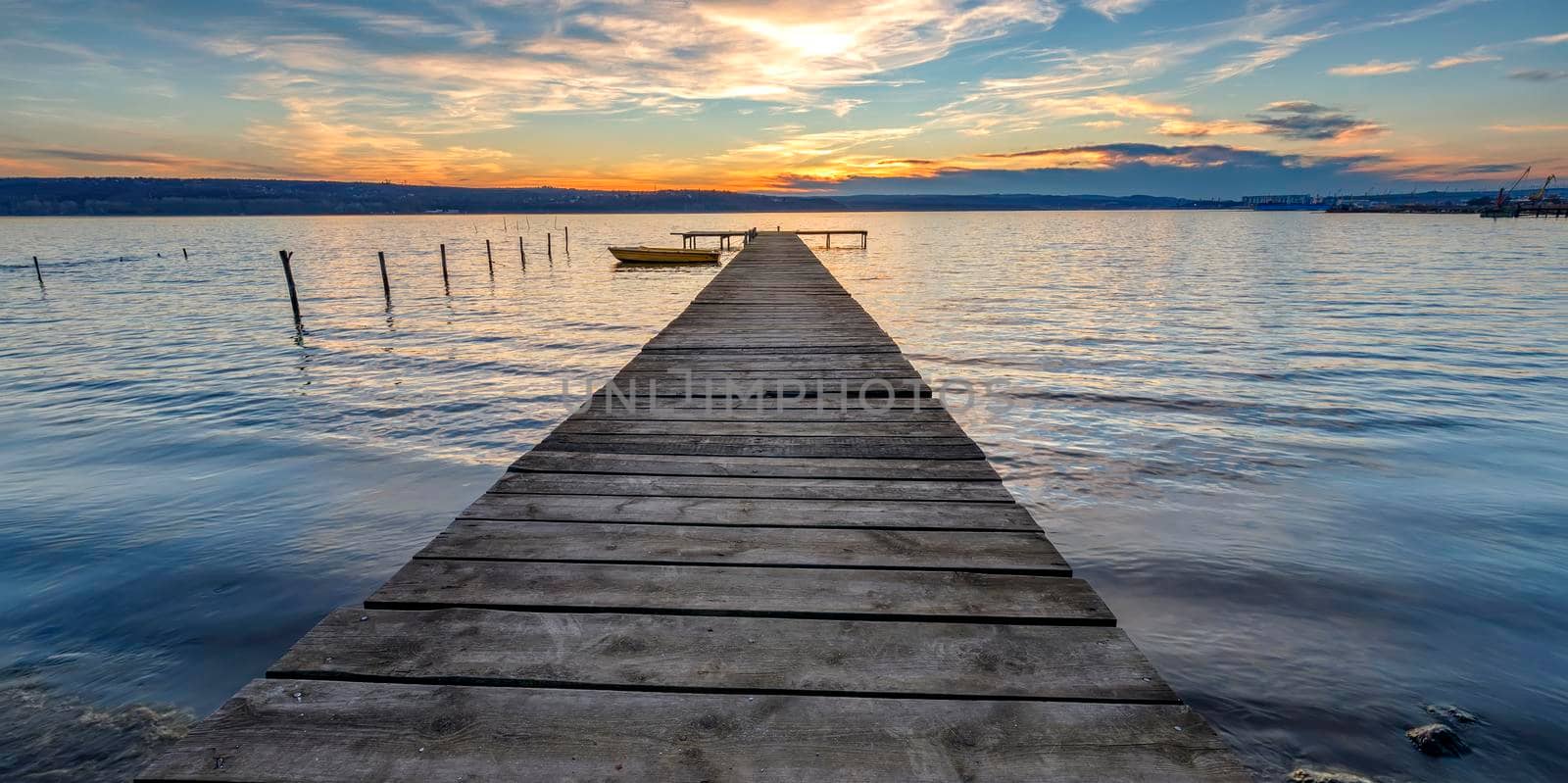 Scenic view of exciting twilight at the shore with a wooden pier and moored boat