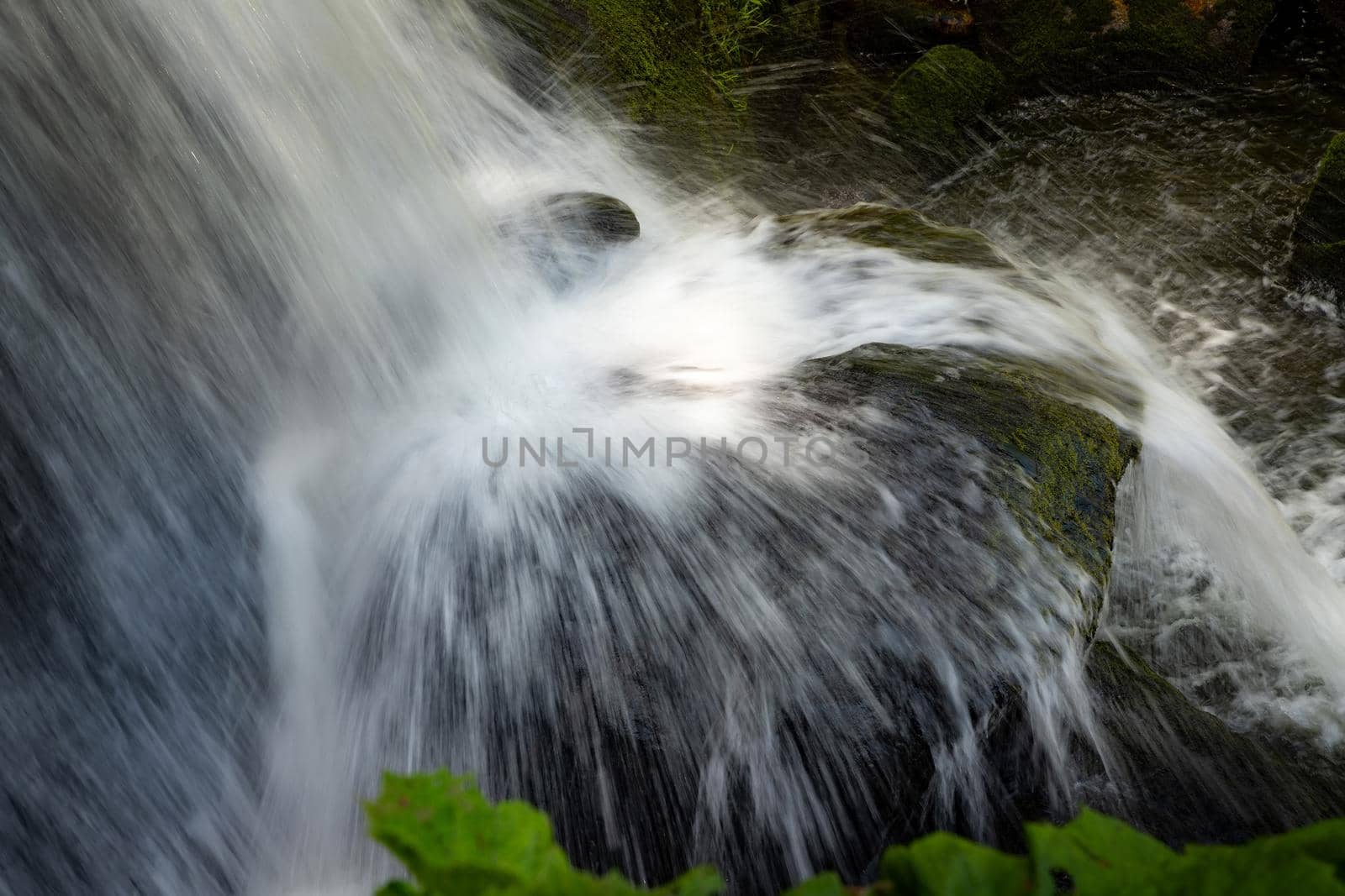 Beauty water splash of a waterfall over a big rock. Close up