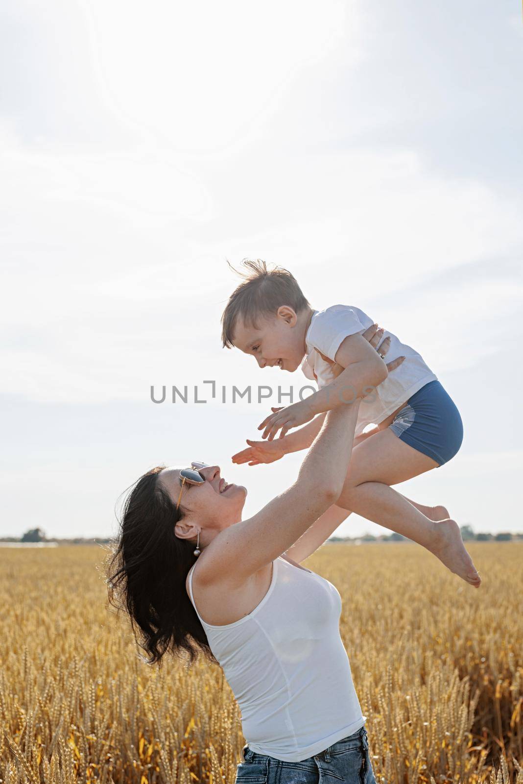 Happy family of mother and infant child walking on wheat field by Desperada