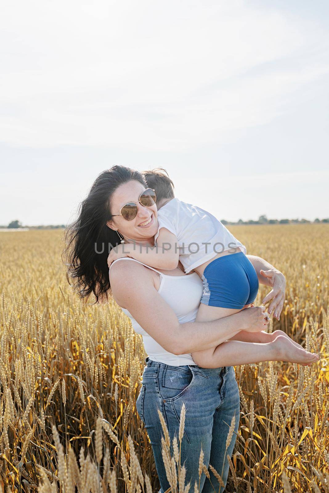Happy family on a summer walk, mother and child walk in the wheat field and enjoy the beautiful nature, at sunset