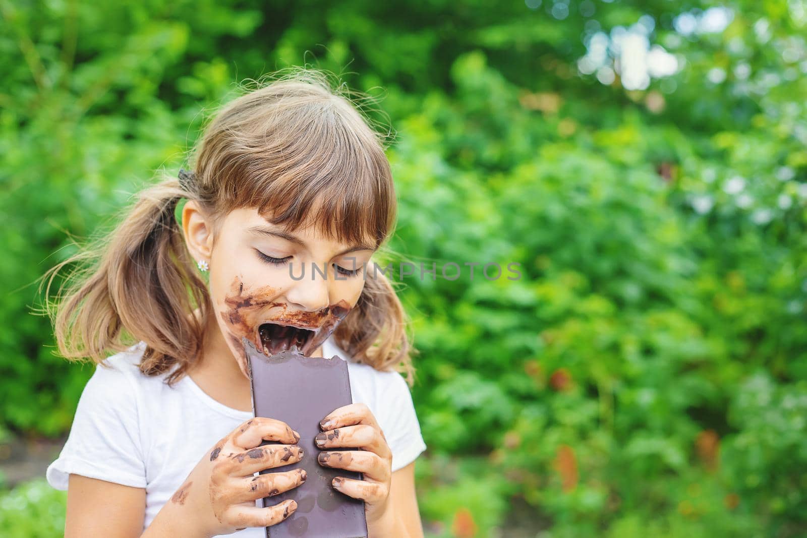 The child eats a chocolate bar. Selective focus. by yanadjana