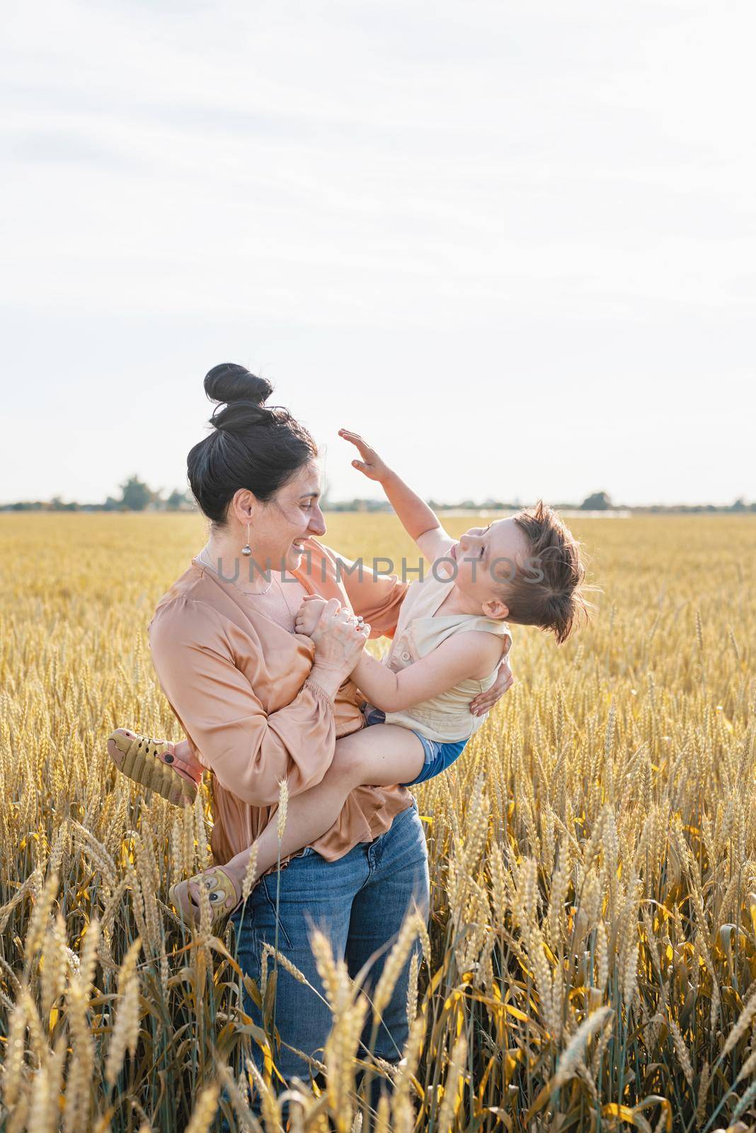 Happy family of mother and infant child walking on wheat field by Desperada