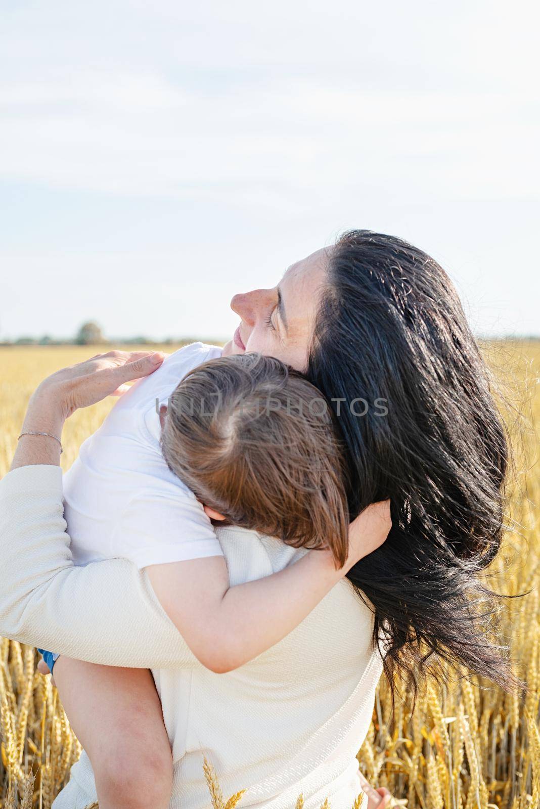 Happy family of mother and infant child walking on wheat field, family portrait by Desperada