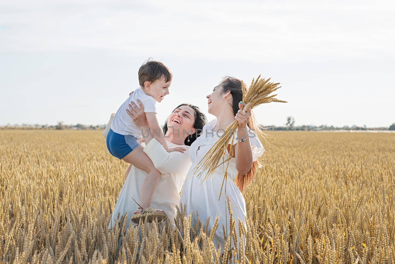 happy family of three people, mother and two children walking on wheat field by Desperada