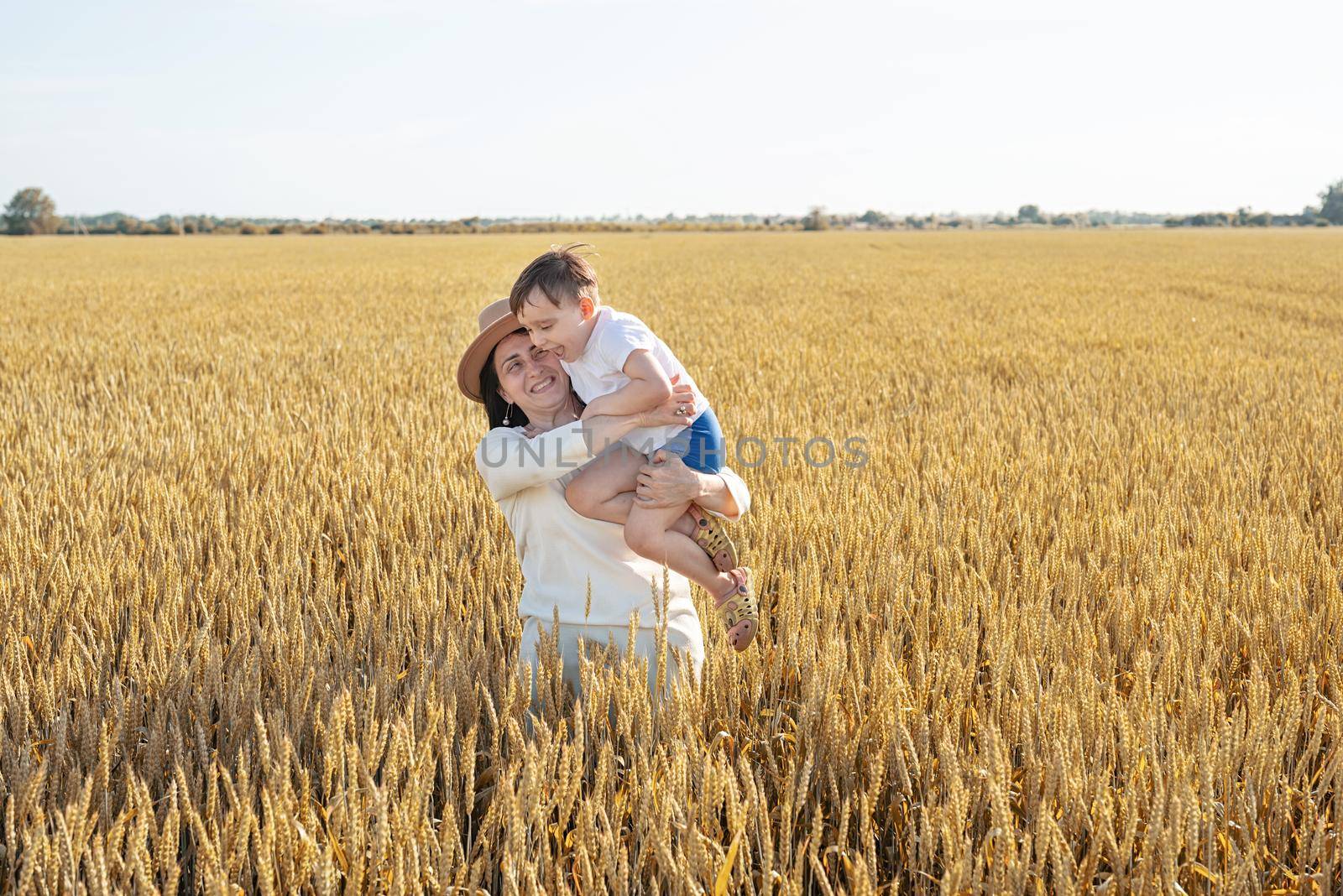 Happy family on a summer walk, mother and child walk in the wheat field and enjoy the beautiful nature, at sunset