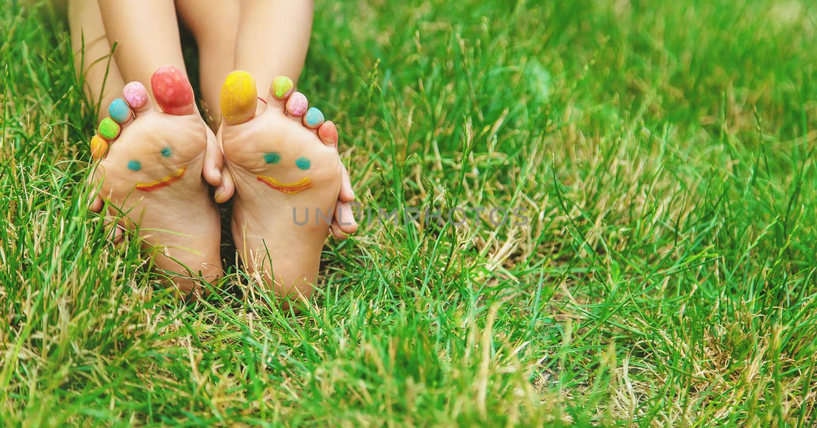 Children's feet with a pattern of paints smile on the green grass. Selective focus. nature.