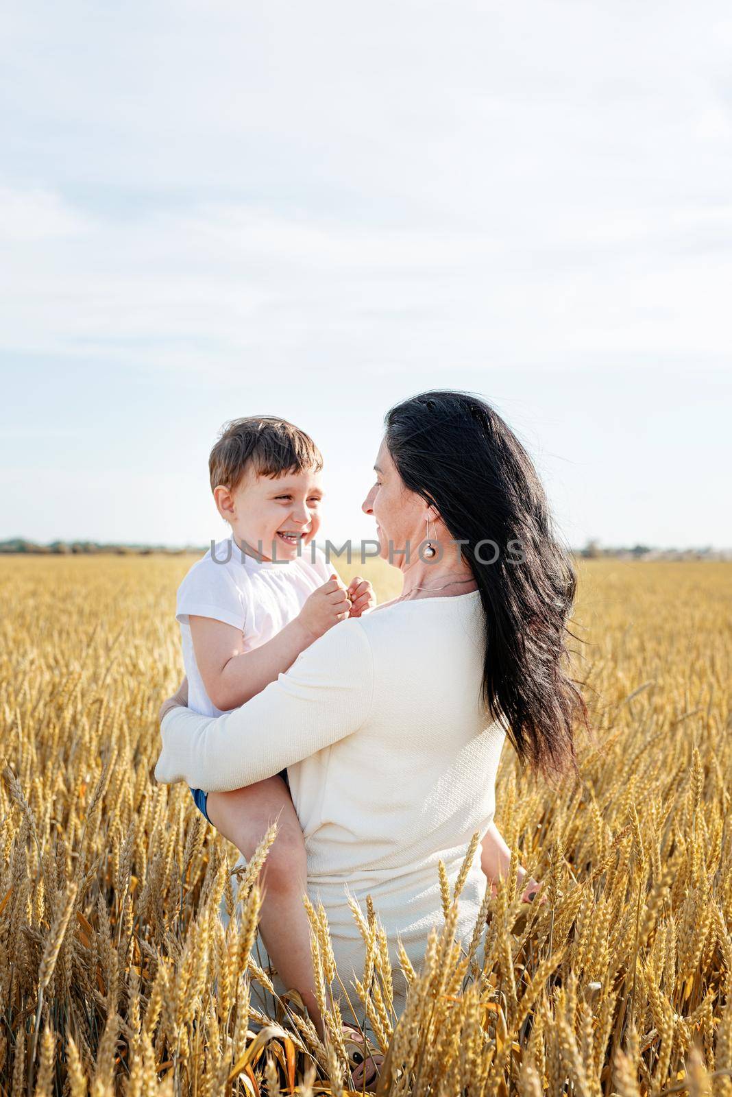 Happy family on a summer walk, mother and child walk in the wheat field and enjoy the beautiful nature, at sunset