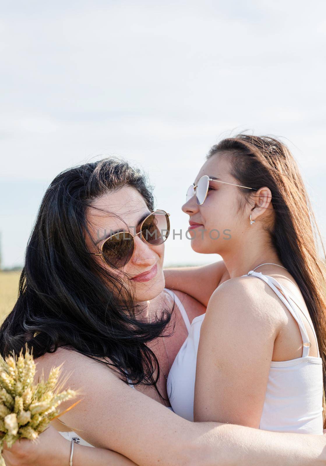 Freedom, friendship concept. Two smiling female friends in white shirts in the wheat field