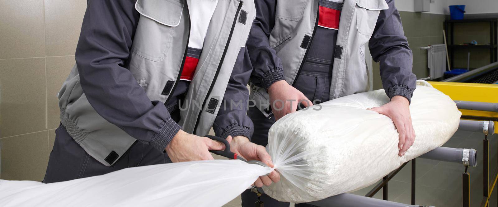 Men workers packing carpet in a plastic bag after cleaning it in automatic washing machine and dryer