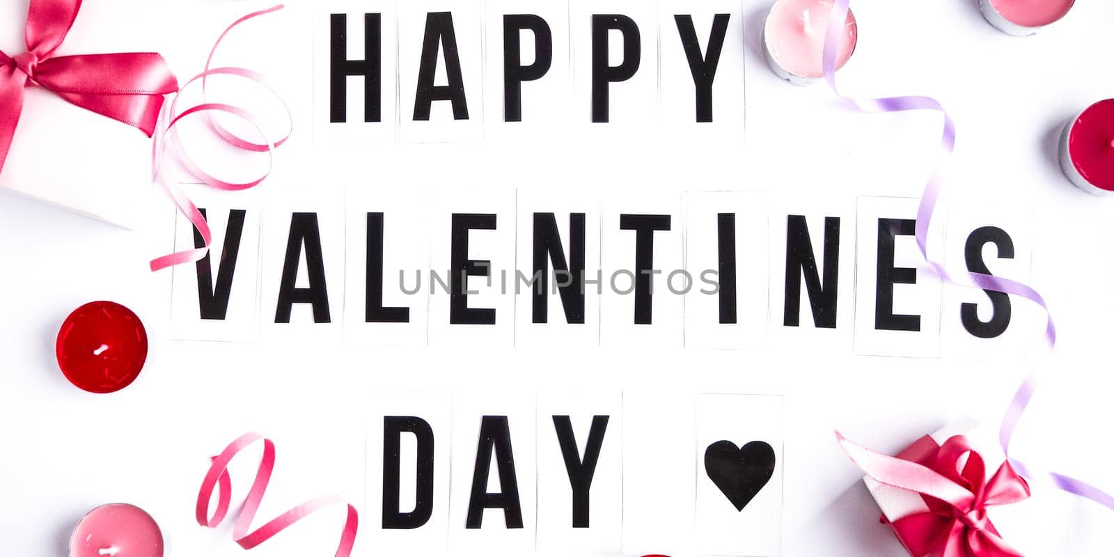 Happy valentines day text on white table background, with gift boxes and candles by anna_stasiia