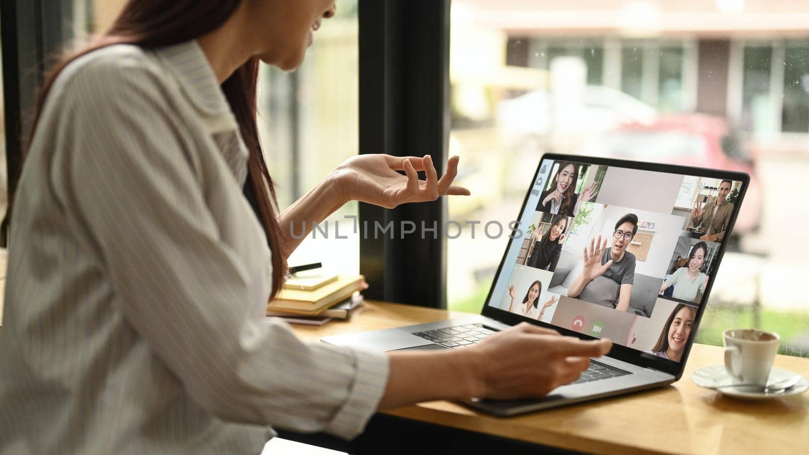 Cropped shot young business woman having online video call on laptop while sitting in modern workplace.