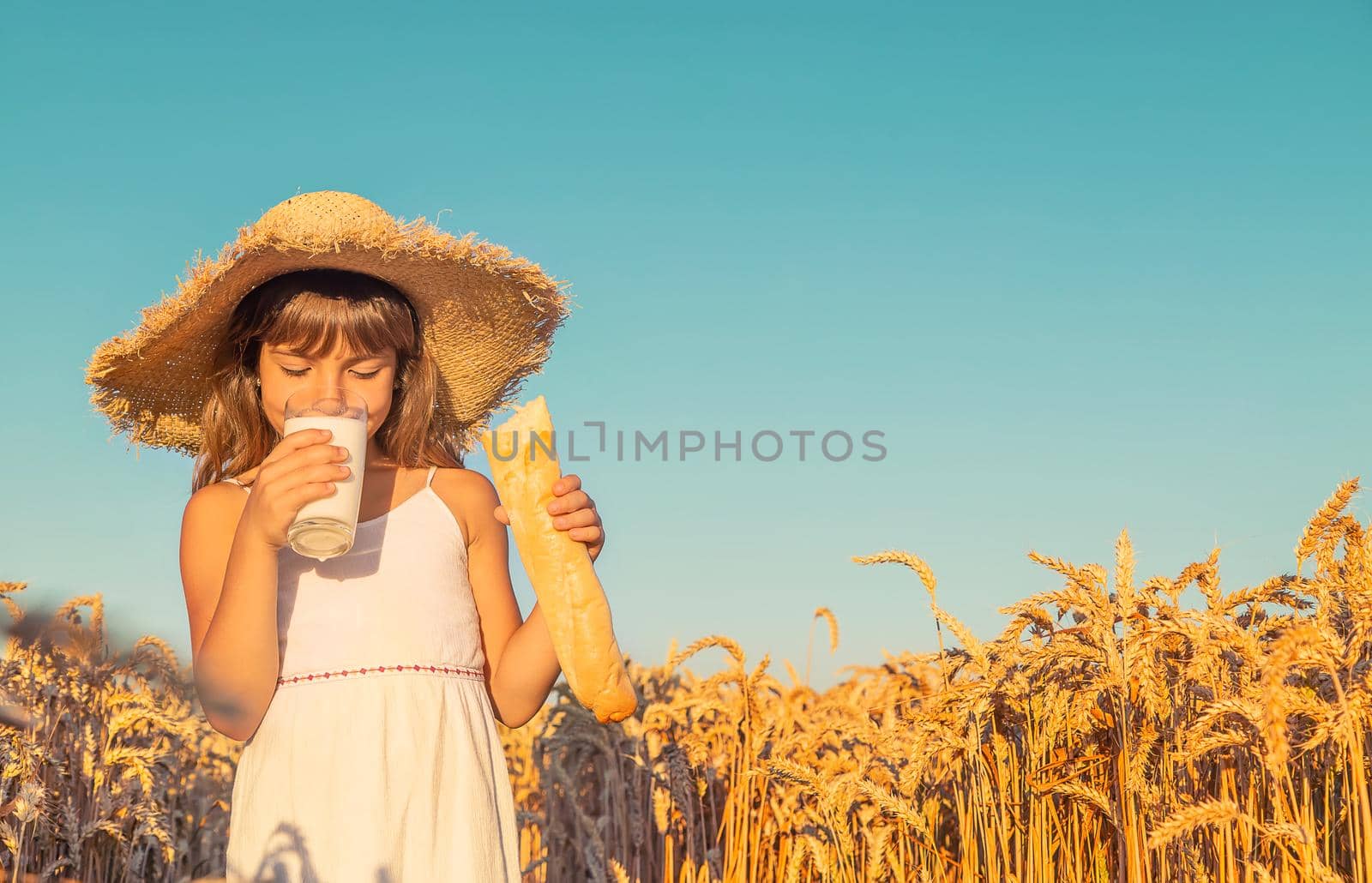 Child with bread and milk in a wheat field. Selective focus. nature.