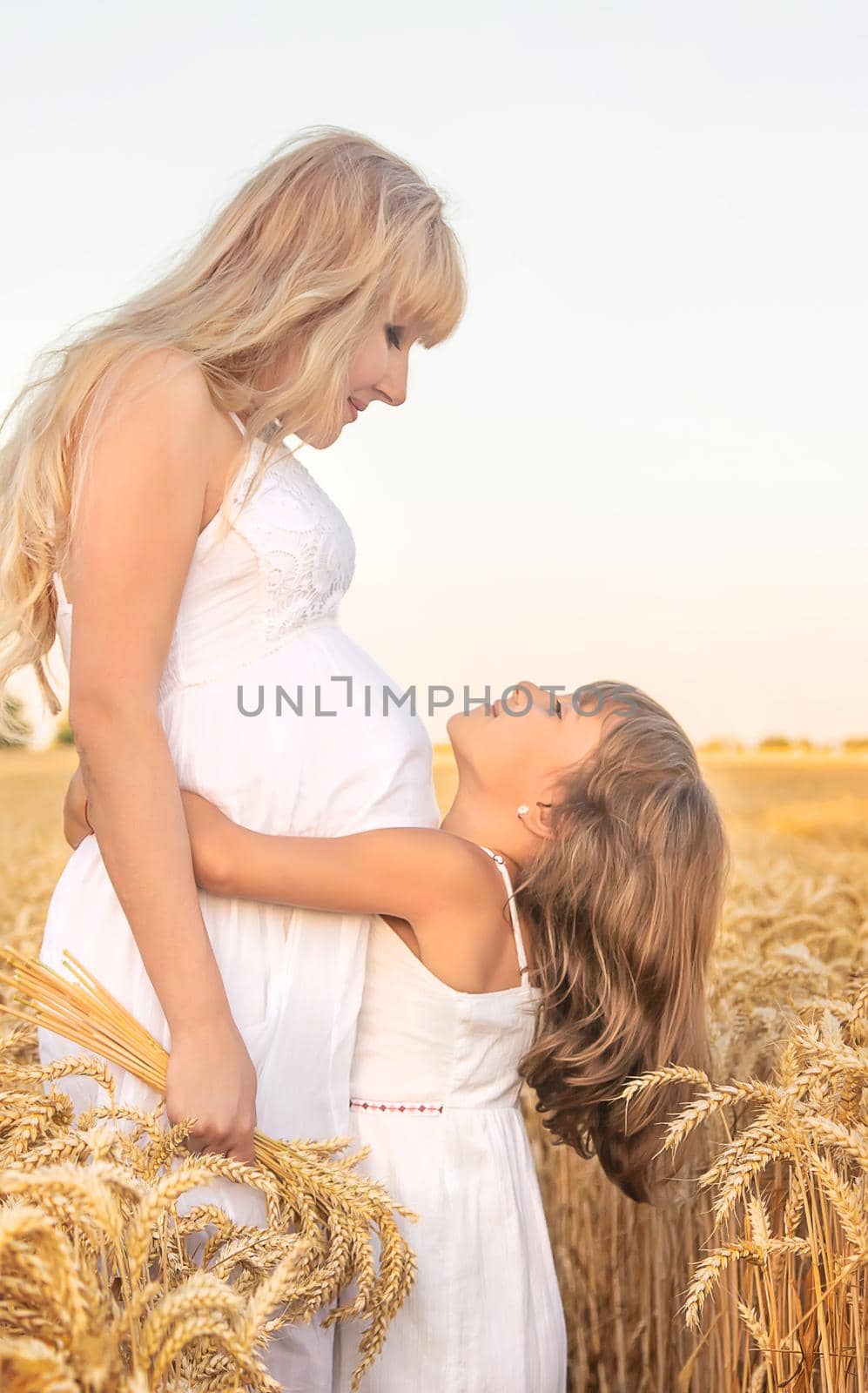 Pregnant woman with daughter in a wheat field. Selective focus. by yanadjana