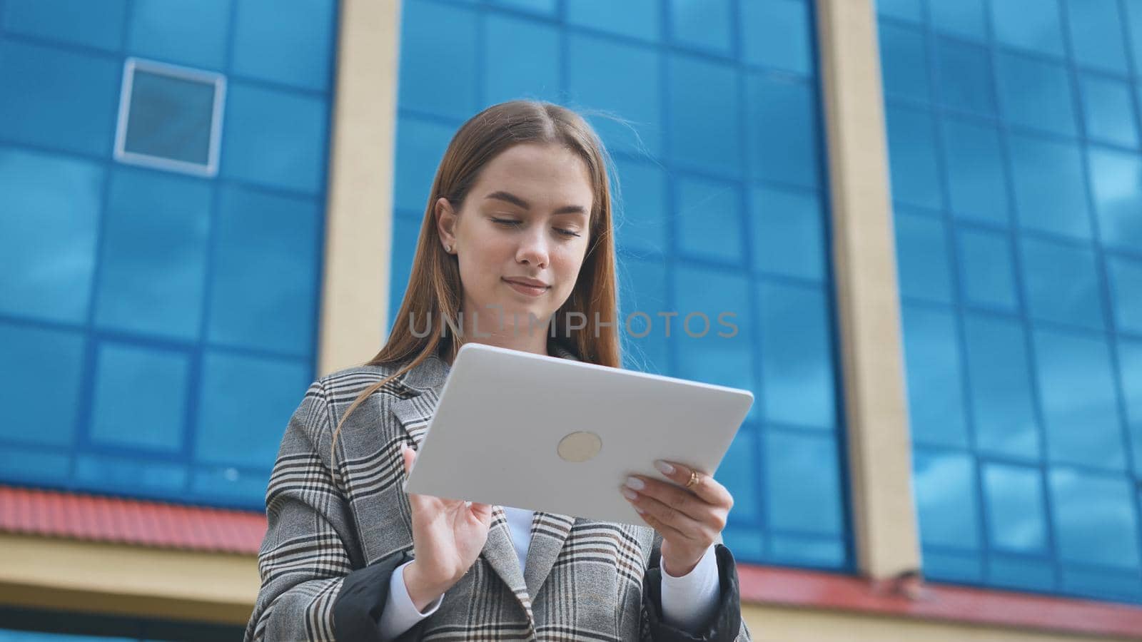 A young girl student works with a white tablet in the city