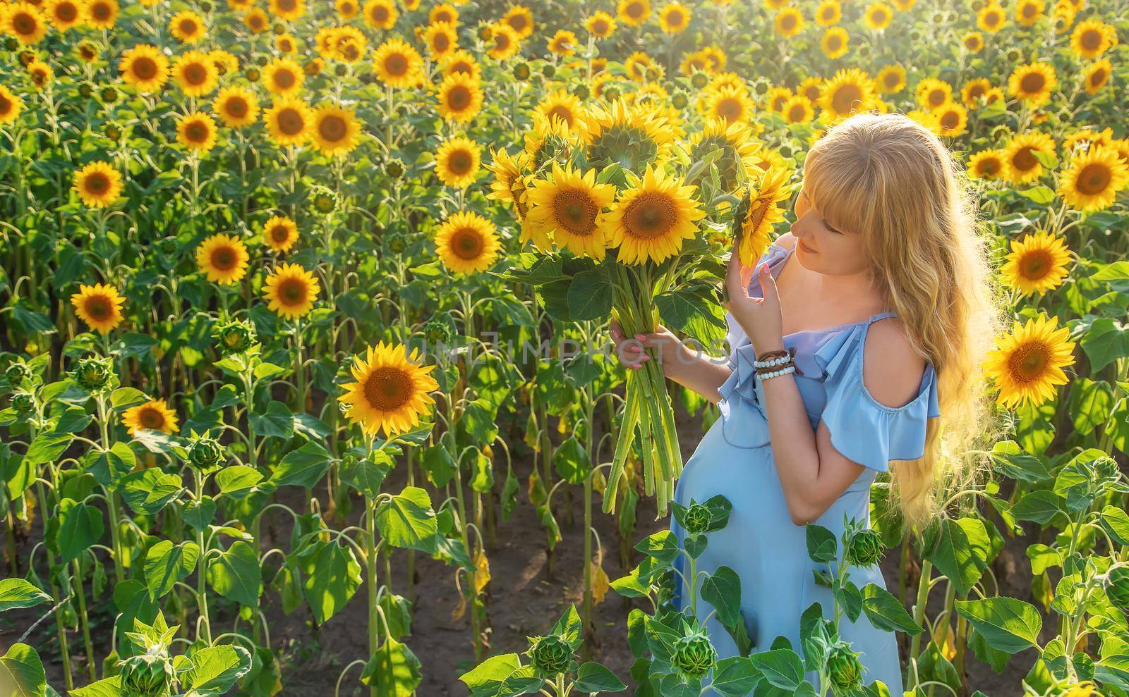 A pregnant woman in a field of sunflowers. Selective focus. by yanadjana