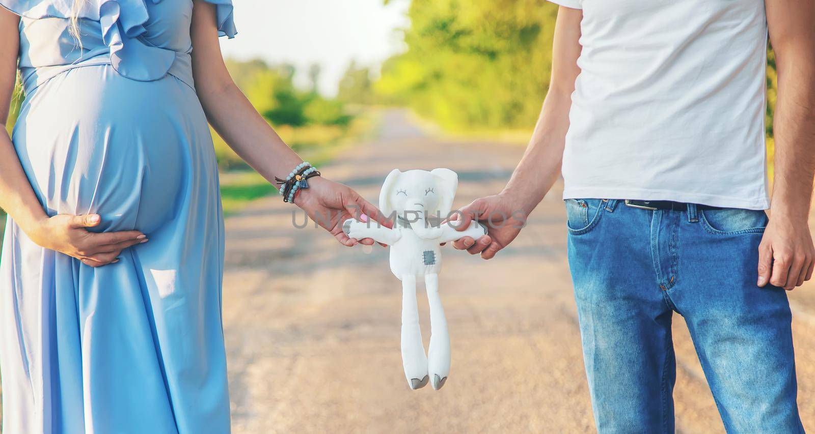 A pregnant woman and a man are holding a toy. Selective focus. nature.