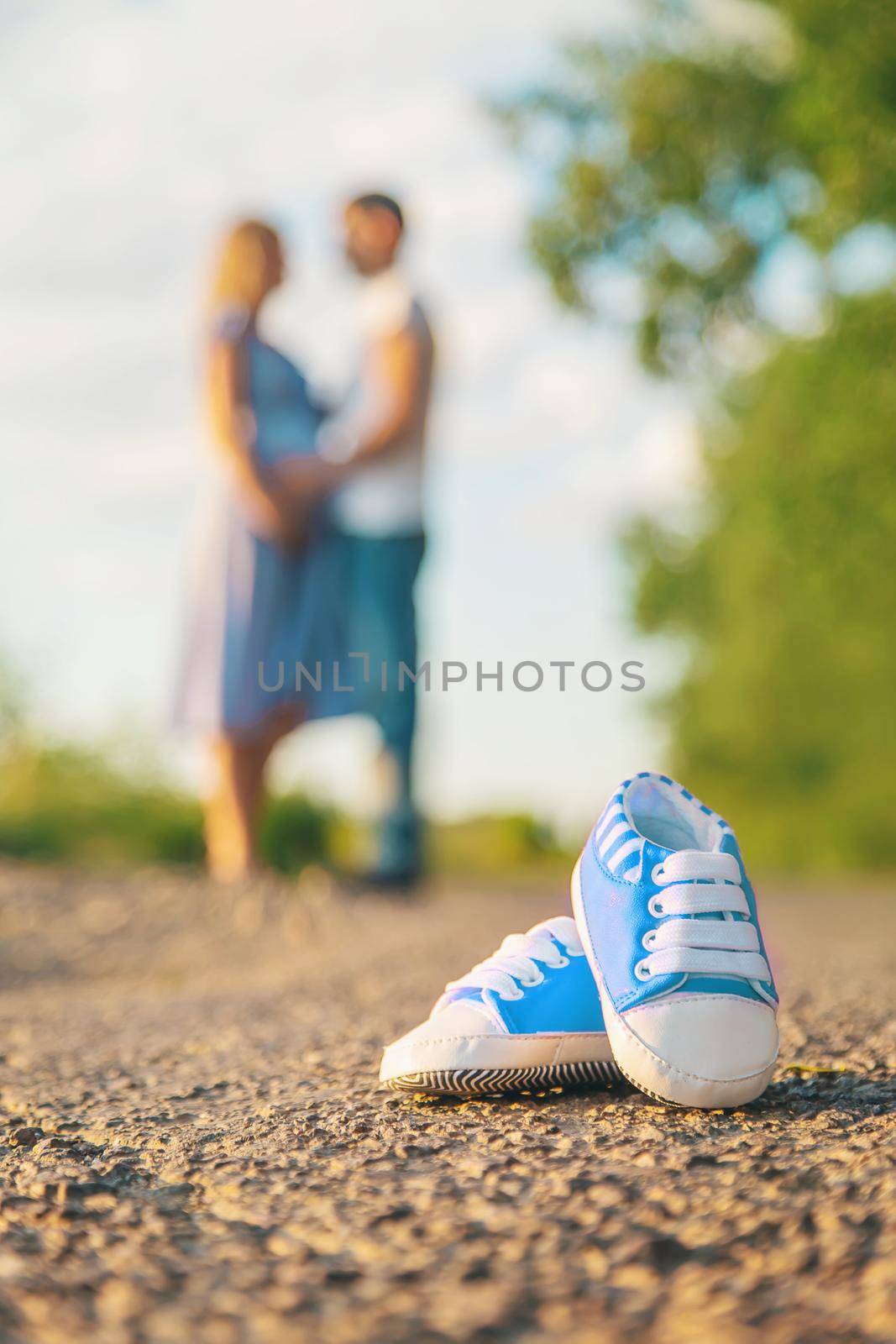 Pregnant woman and man baby shoes. Selective focus. nature.