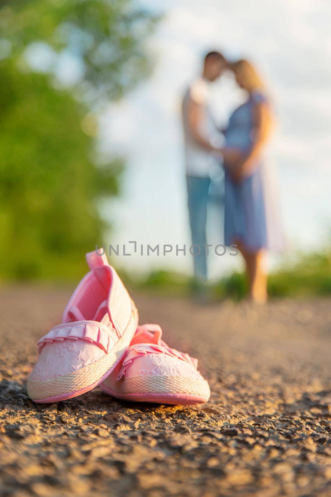 Pregnant woman and man baby shoes. Selective focus. nature.