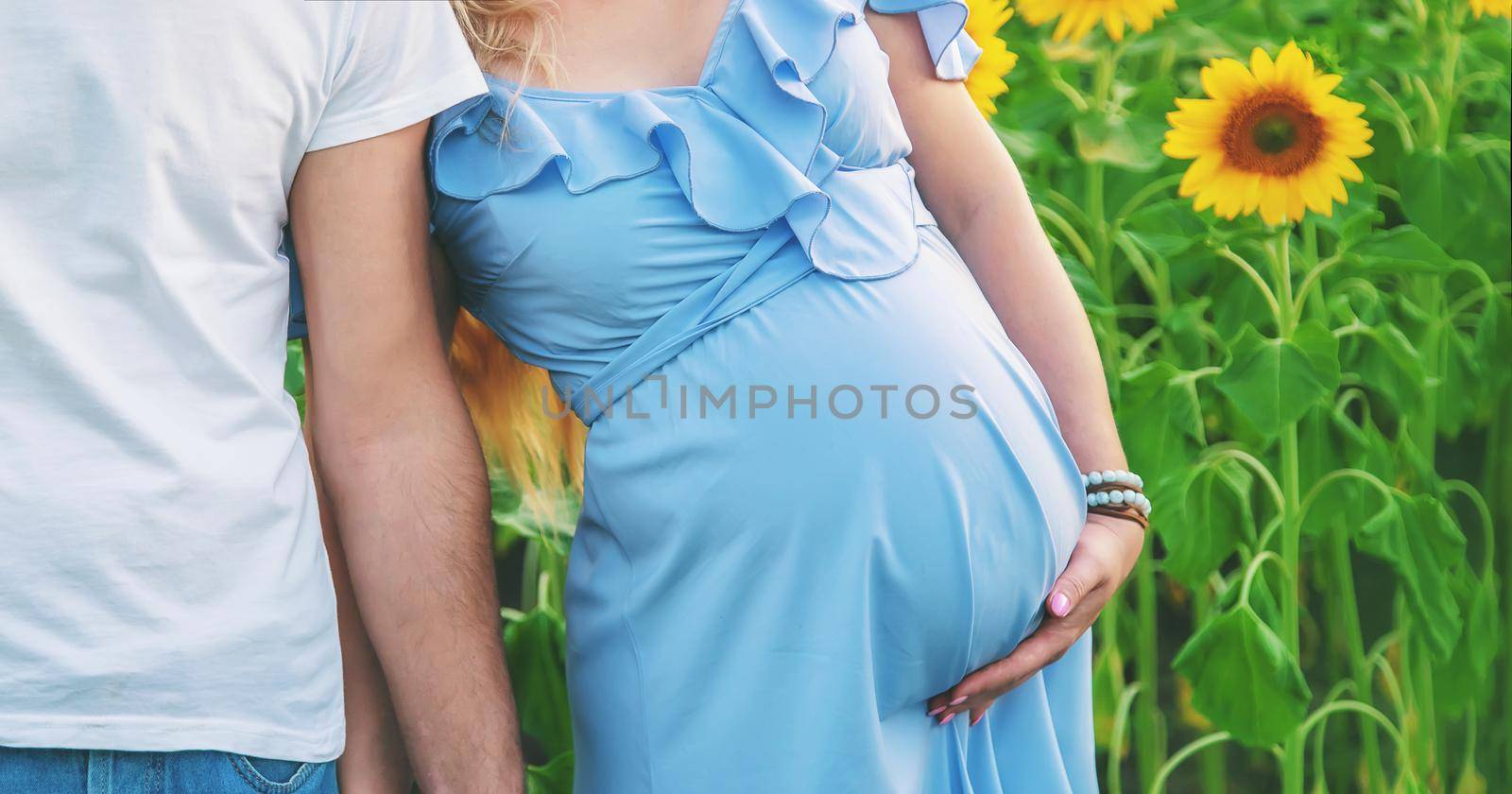 Pregnant woman and man in a field of sunflowers. Selective focus. nature.
