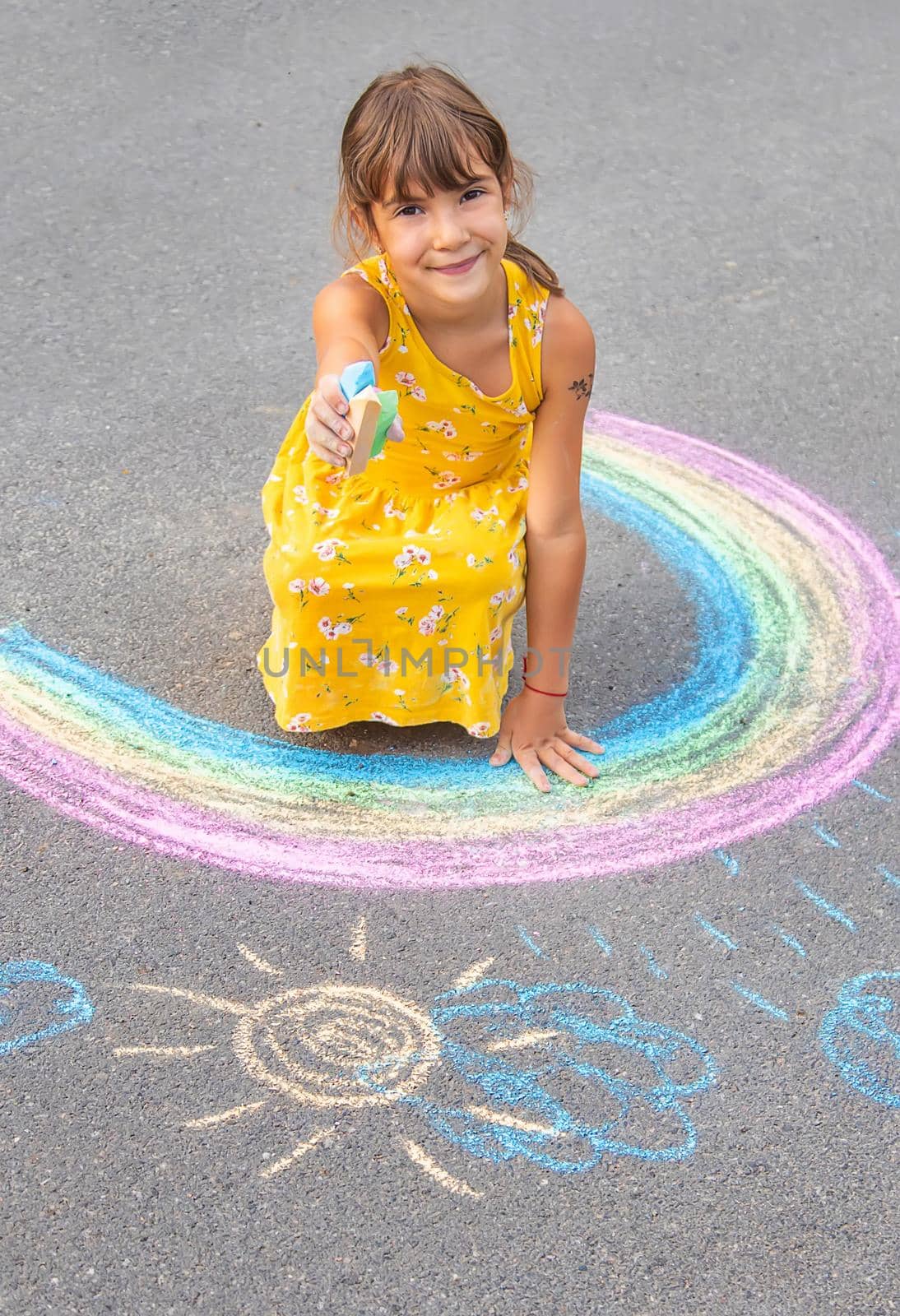 A child draws a rainbow on the asphalt. Selective focus. kid.