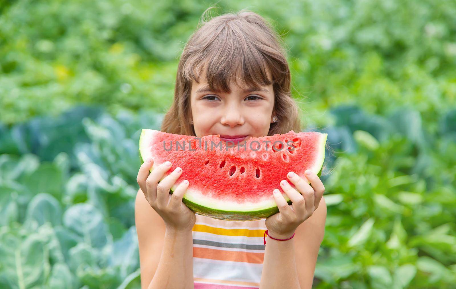 A child on a picnic eats a watermelon. Selective focus.