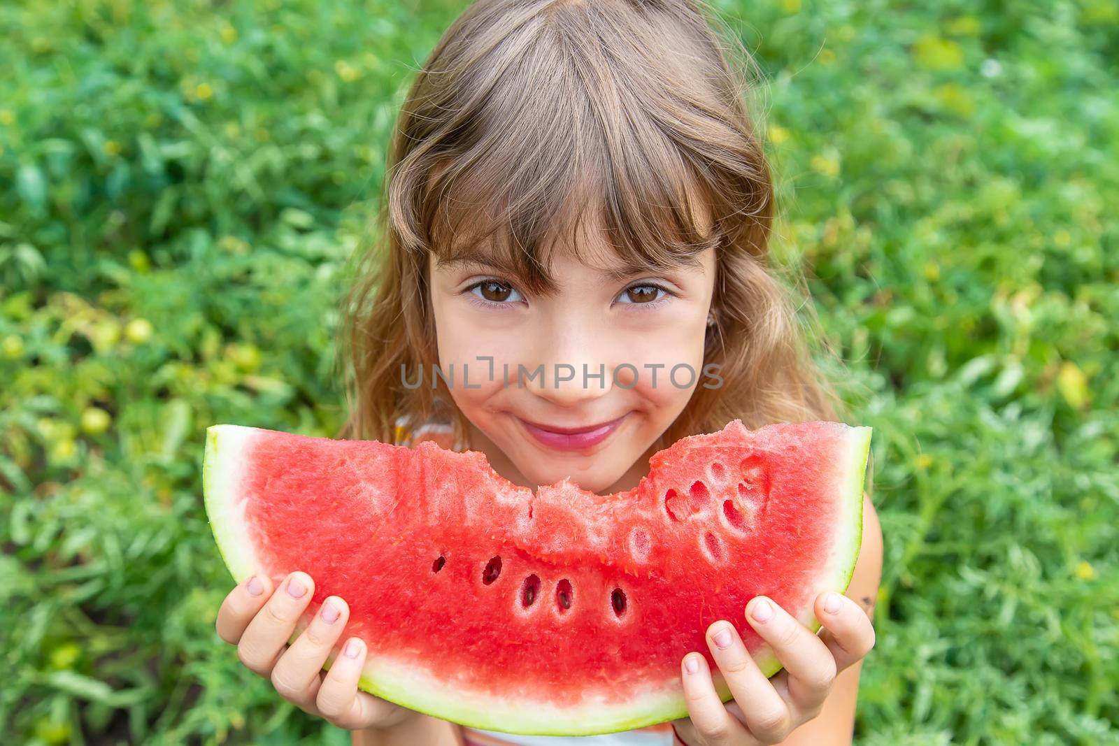 A child on a picnic eats a watermelon. Selective focus. by yanadjana