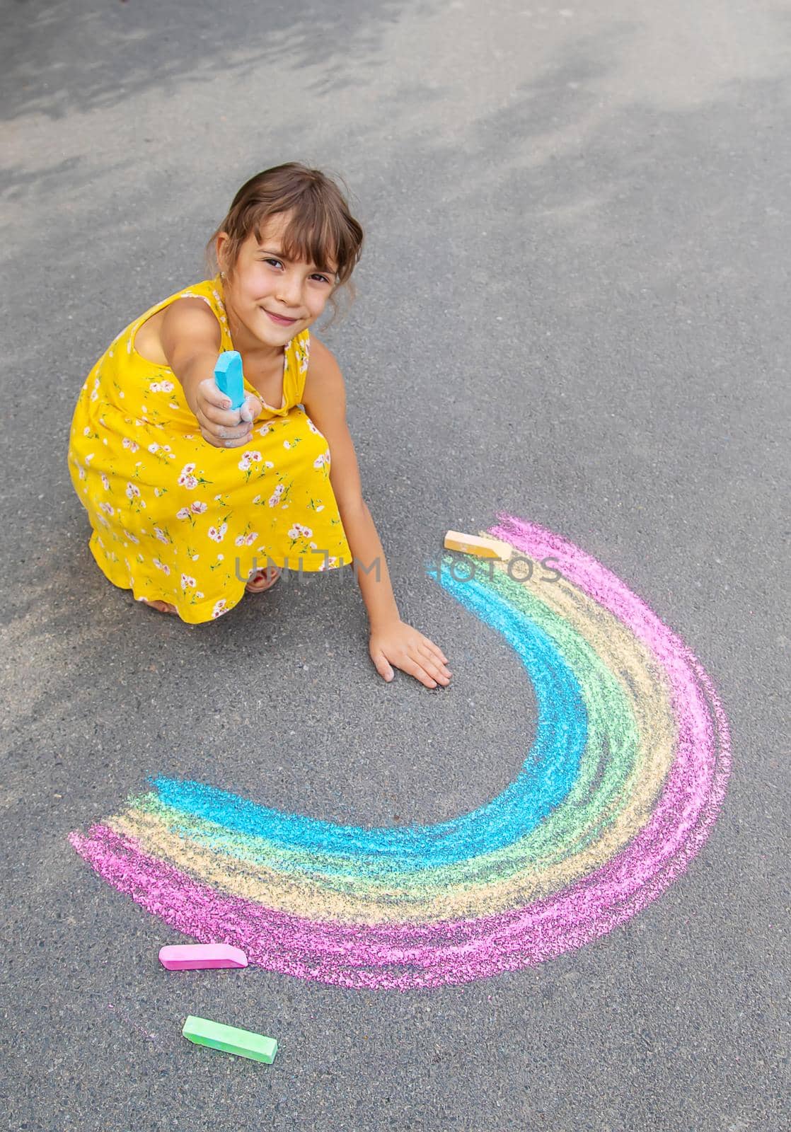 A child draws a rainbow on the asphalt. Selective focus. kid.