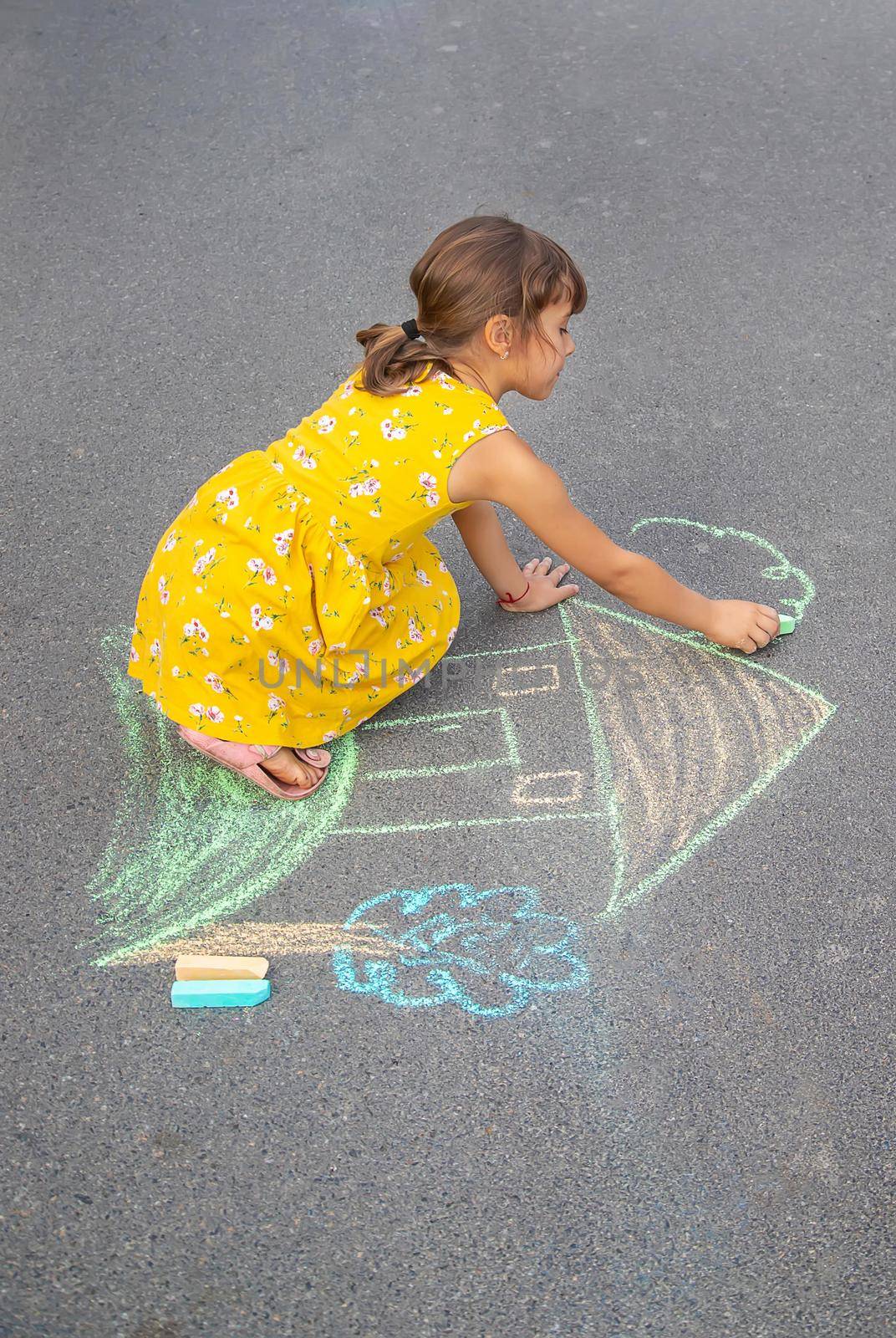 The child draws a house on the asphalt. Selective focus. kid.