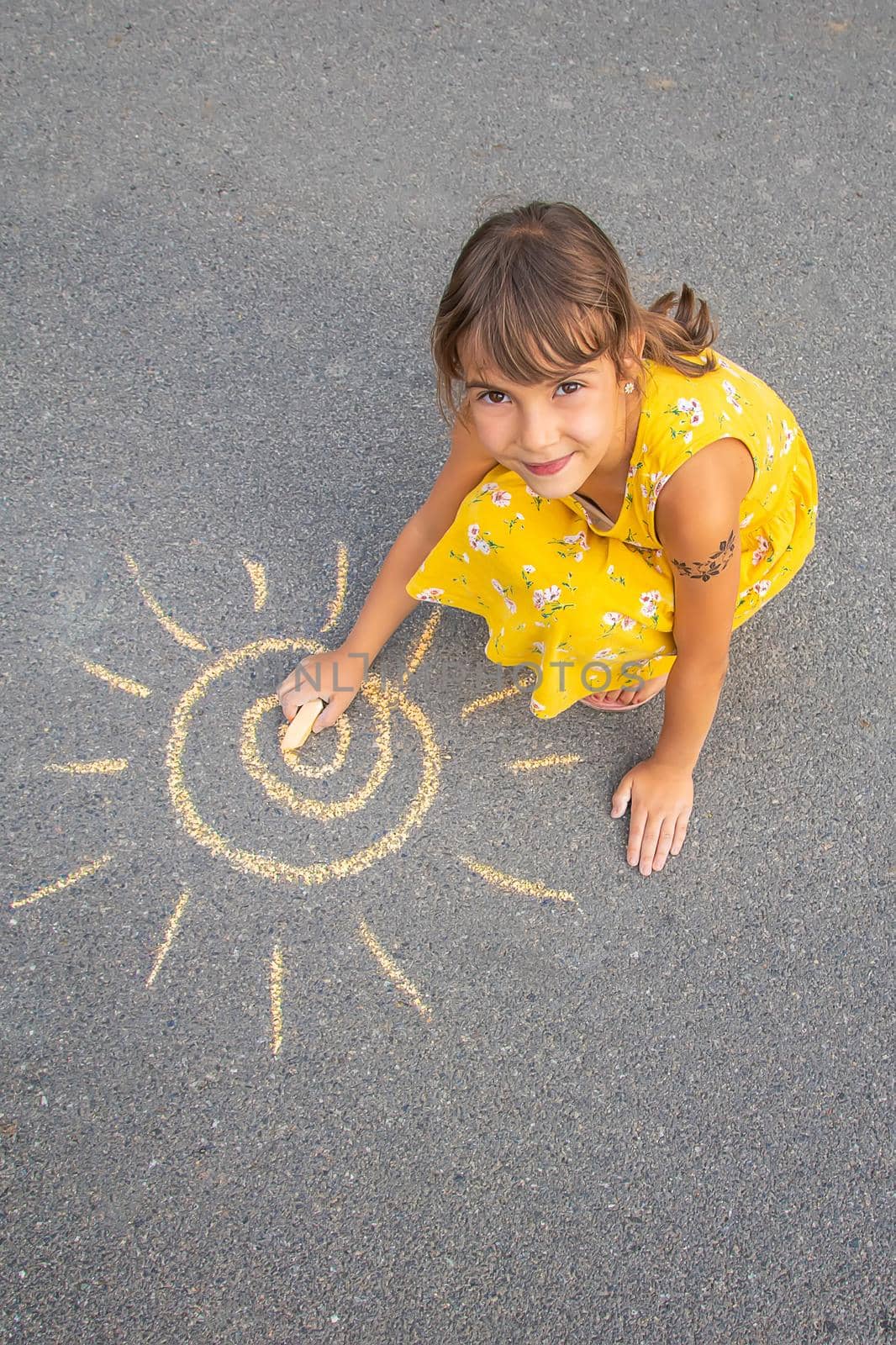The child draws the sun on the asphalt. Selective focus. by yanadjana