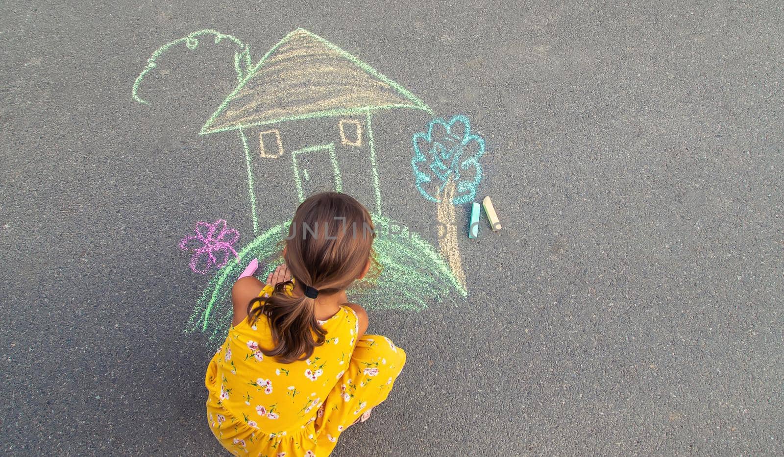 The child draws a house on the asphalt. Selective focus. by yanadjana