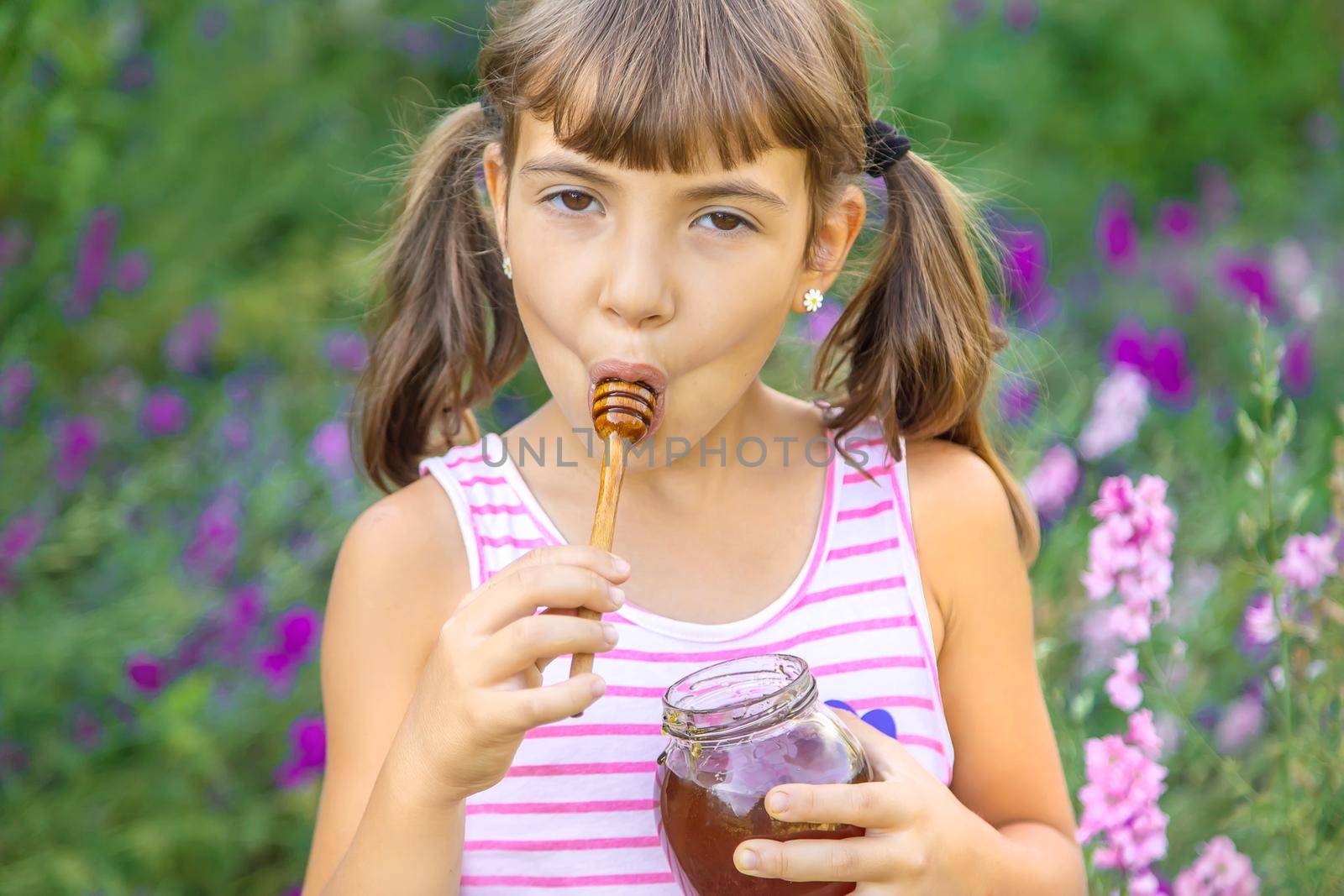 Child eats honey summer photo. Selective focus. by yanadjana