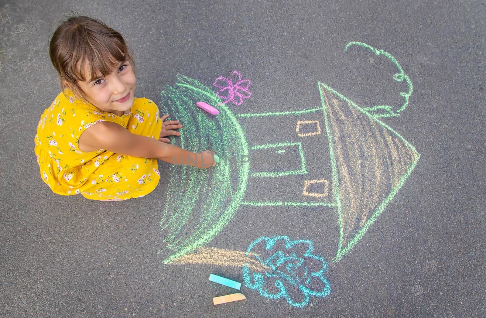 The child draws a house on the asphalt. Selective focus. by yanadjana