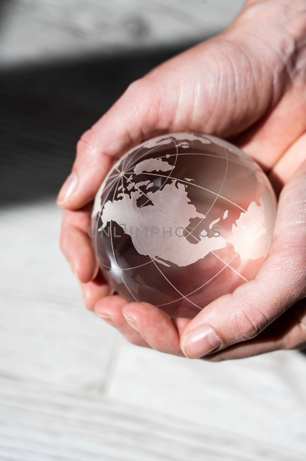 Close-up of female hands with a crystal globe on a woody background