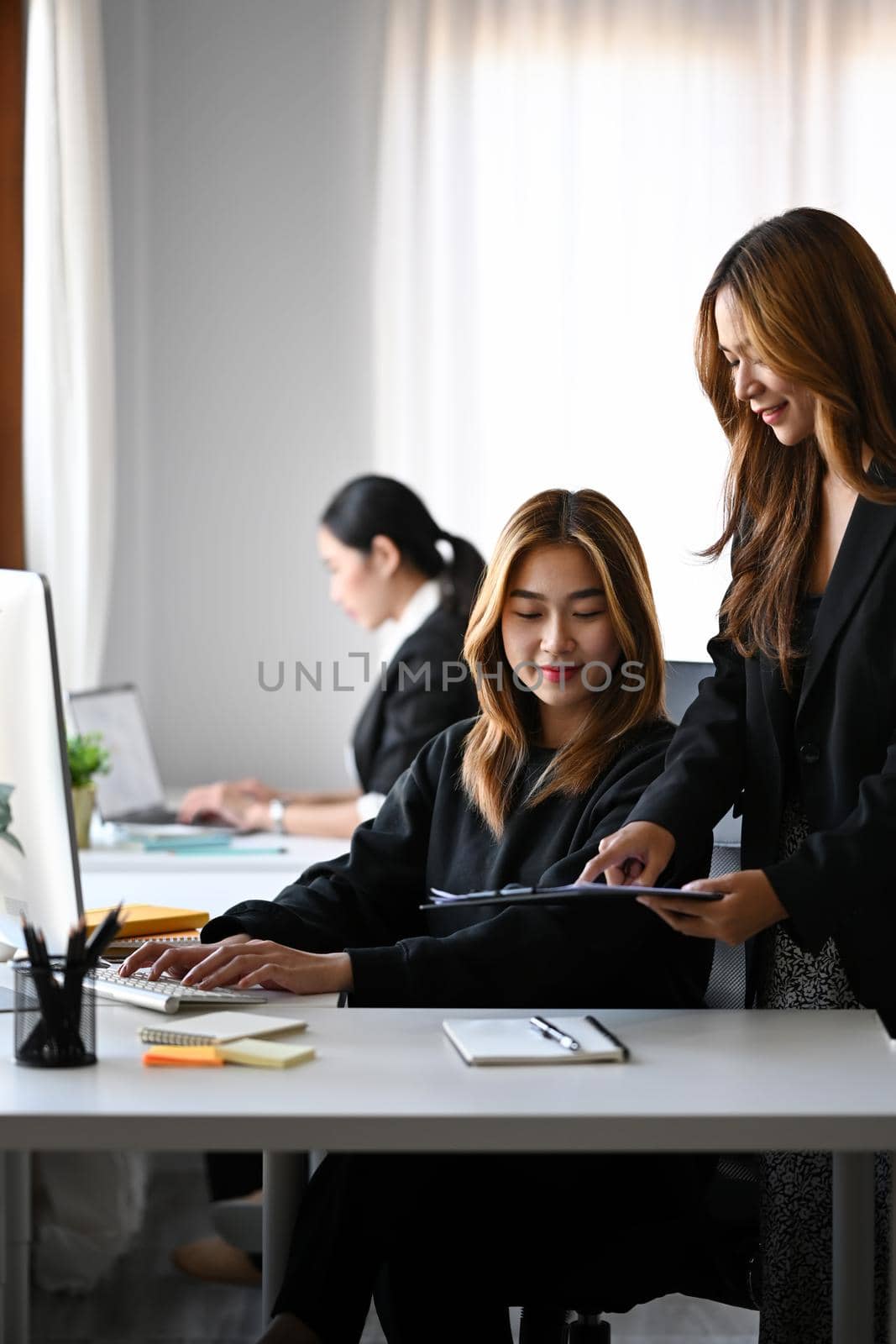 Two asian businesswomen working together at office. by prathanchorruangsak