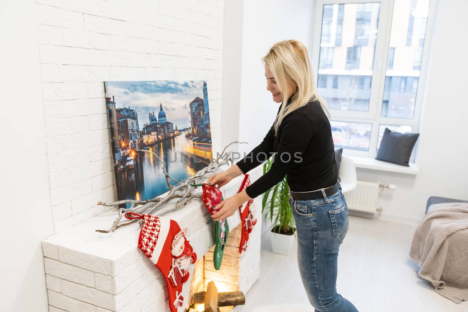 woman hangs Christmas socks on the fireplace.