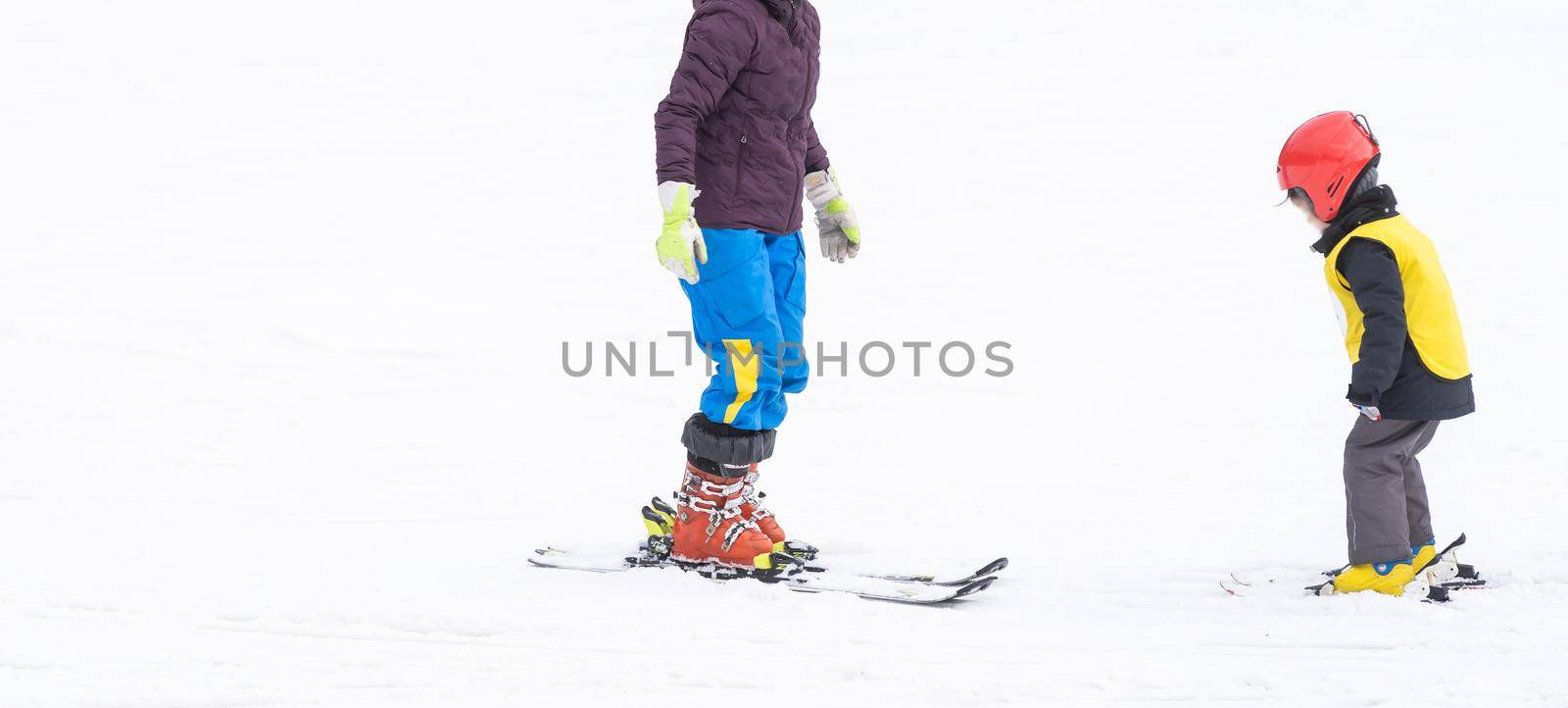 Instructor and little child skiing. toddler kid with safety helmet. Ski lesson for young children. Winter sport. Little skier.