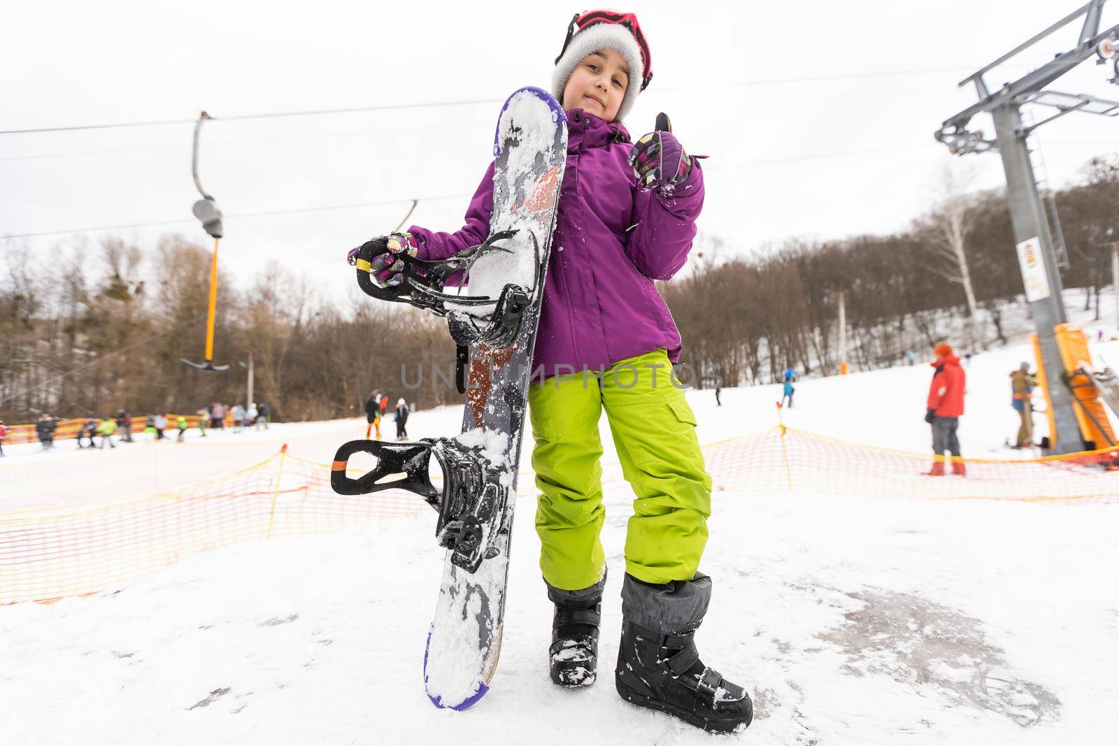 little cute girl learning to ride a children's snowboard, winter sports for the child, safety of active sports