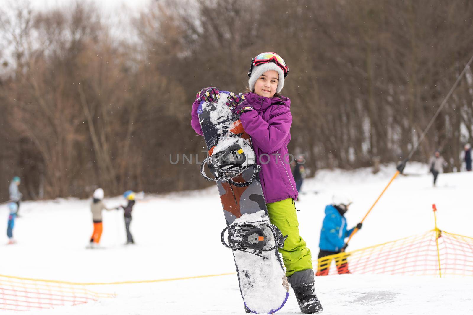 little cute girl learning to ride a children's snowboard, winter sports for the child, safety of active sports