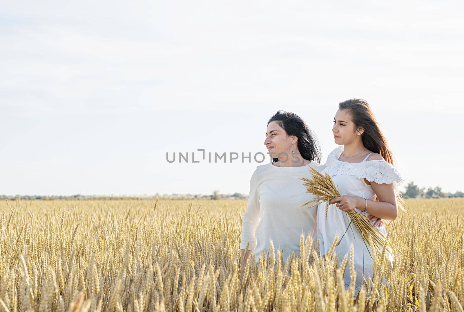 Two smiling female friends in the wheat field by Desperada