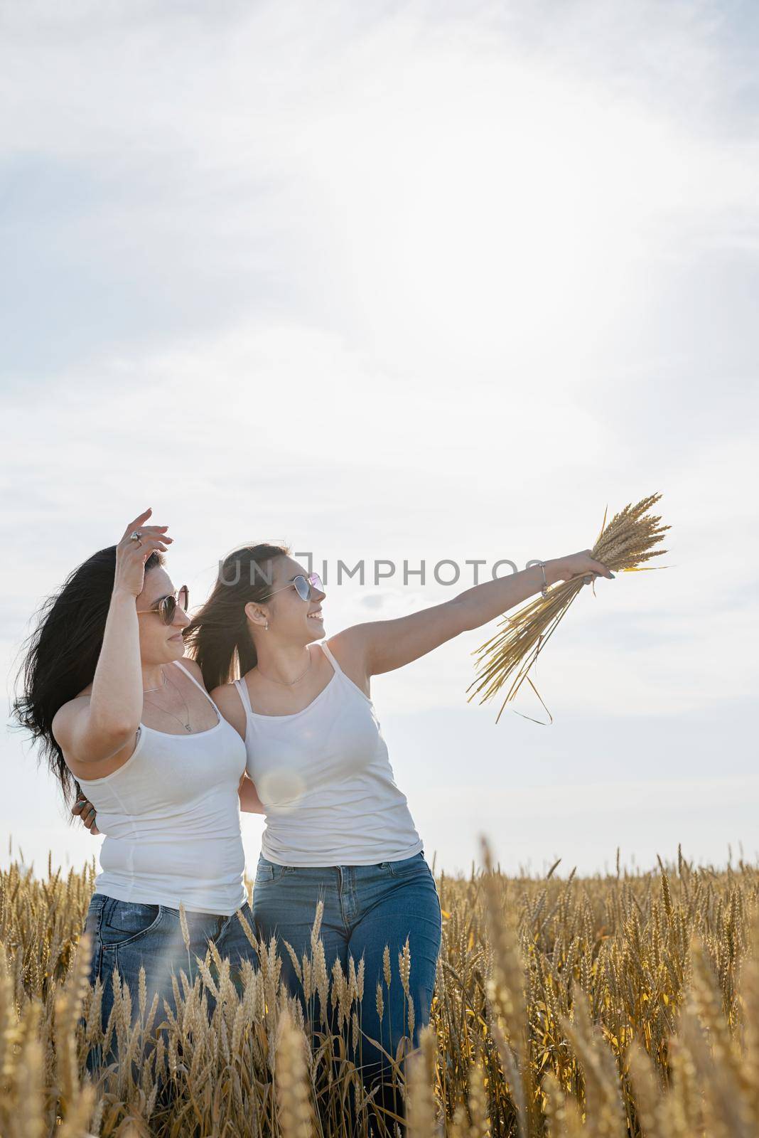 Two smiling female friends in the wheat field by Desperada