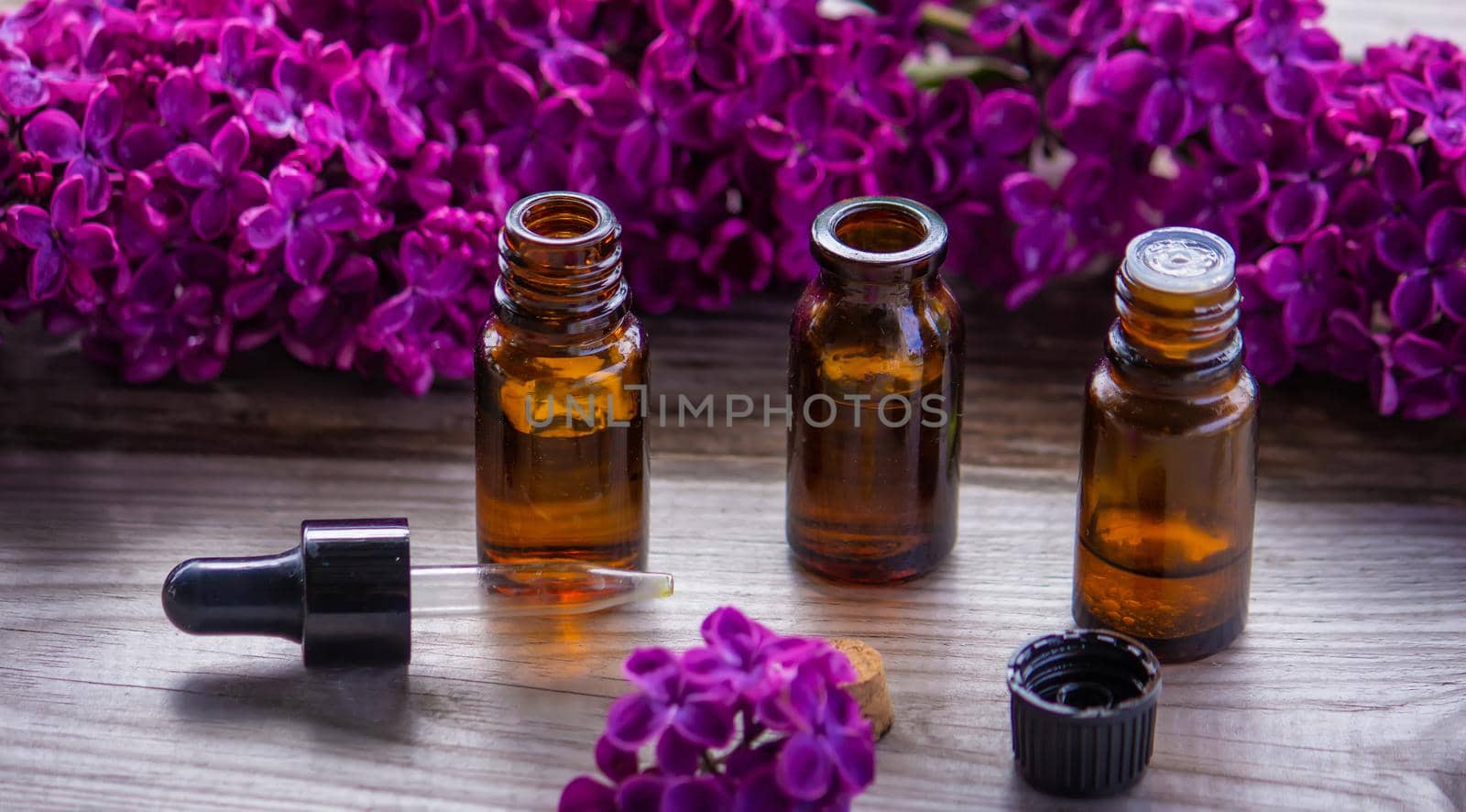 Lilac essential oil in a small bottle. Selective focus. Nature.