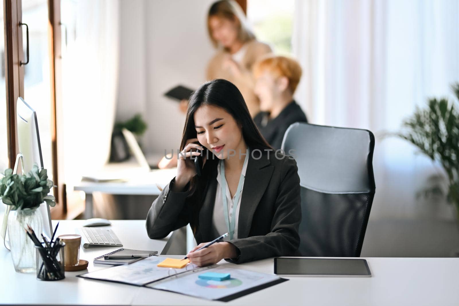 Attractive businesswoman checking statistics information and talking on mobile phone.